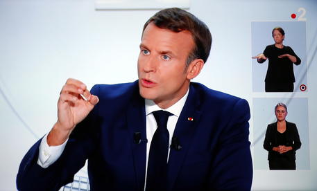 epa08744979 A picture of TV screen shows French President Emmanuel Macron speaking during an interview on the situation of the COVID-19 outbreak, caused by the novel coronavirus, in Vendemian, France, 14 October 2020. Macron asked the french citizens to reduce their movement and establish a curfew from 17 October 2020.  EPA/Guillaume Horcajuelo