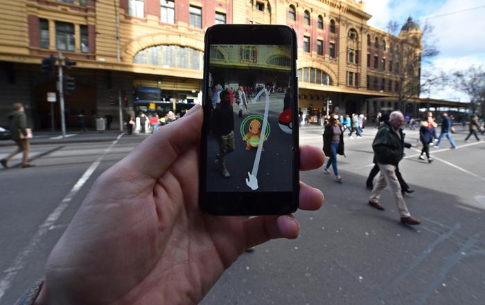 epa05421251 A person (partially obscured) plays with the new game 'Pokemon Go' on a smartphone on Flinders Street in Melbourne, Victoria, Australia, 12 July 2016. Pokemon Go, a Global Positioning System (GPS) based augmented reality mobile game, is proving to be 'enormously' popular since software development company Niantic opened access to it on 06 July in the US.  EPA/JULIAN SMITH AUSTRALIA AND NEW ZEALAND OUT
