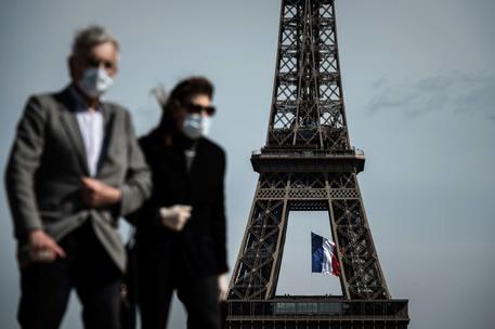 (FILES) In this file photo taken on May 11, 2020, a man and a woman wearing face masks walk on Trocadero Plaza as a French national flag flies on the Eiffel Tower in background in Paris on the first day of France's easing of lockdown measures in place for 55 days to curb the spread of the COVID-19 pandemic, caused by the novel coronavirus. - Wearing a mask will be compulsory in parts of Paris and its wider region from August 10, 2020, to combat a rise in coronavirus infections in and around the French capital, the police said. The mask will be obligatory for all those aged 11 and over from 8:00 am (0600 GMT) on August 10 