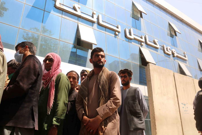 epa09428742 Afghans gather outside a closed bank in Kabul, Afghanistan, 25 August 2021. Taliban spokesperson Zabiullah Mujahid said in a press conference on 24 August, that evacuation must be completed by August 31 and they will not allow Afghans to go to the airport from now on.  EPA/AKHTER GULFAM