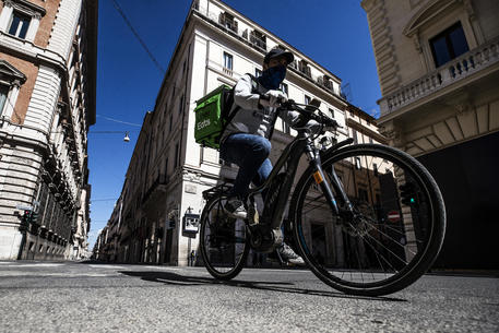 A Uber Eats rider passes on a deserted Via del Corso during the emergency blockade of the Coronavirus Covid-19 in Rome, Italy, 26 April 2020. ANSA/ANGELO CARCONI