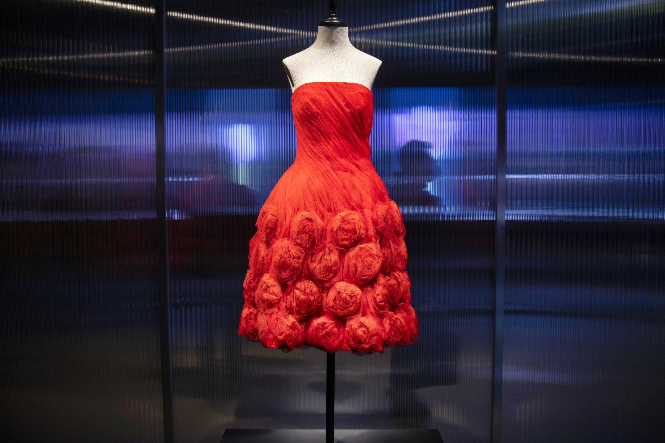epa08920194 A dress is on display as visitors stand behind a transparent screen at an art exhibition of the Italian fashion brand Valentino in Shanghai, China, 05 January 2021. The exhibit titled 'Re-Signify Part One Shanghai' features creations from current collections of Maison Valentino and its archives and runs at Shanghai's Power Station of Art  Museum until 17 January.  EPA/ALEX PLAVEVSKI