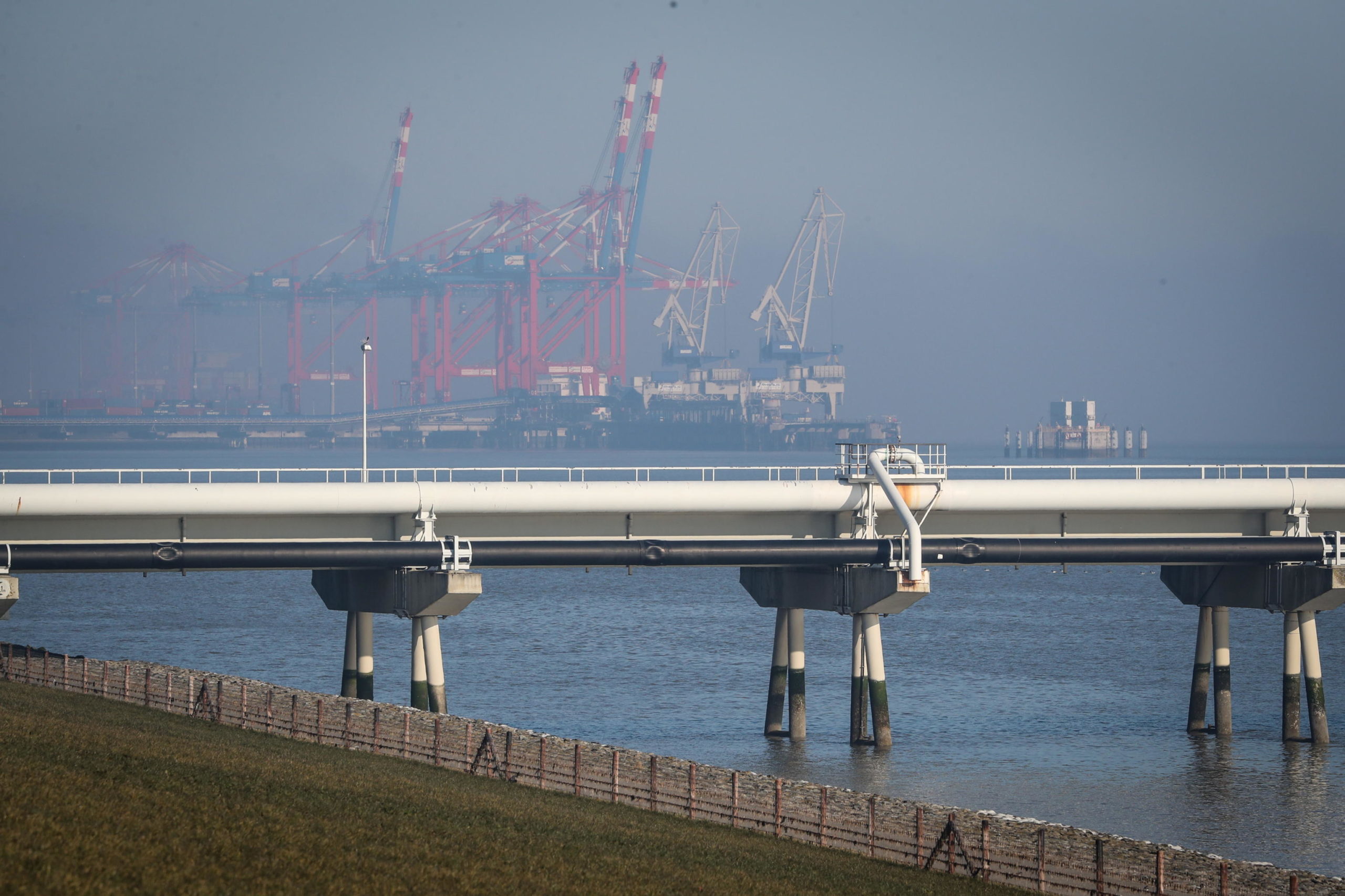 epa09798648 The pier of Nord West Oelleitung (NWO) crude oil pipeline operator with the Jade Weser Port in the background at the port of Wilhelmshaven, northern Germany, 03 March 2022. Wilhelmshaven is one of three possible locations for Germany's planned liquid natural gas (LNG) terminals.  EPA/FOCKE STRANGMANN