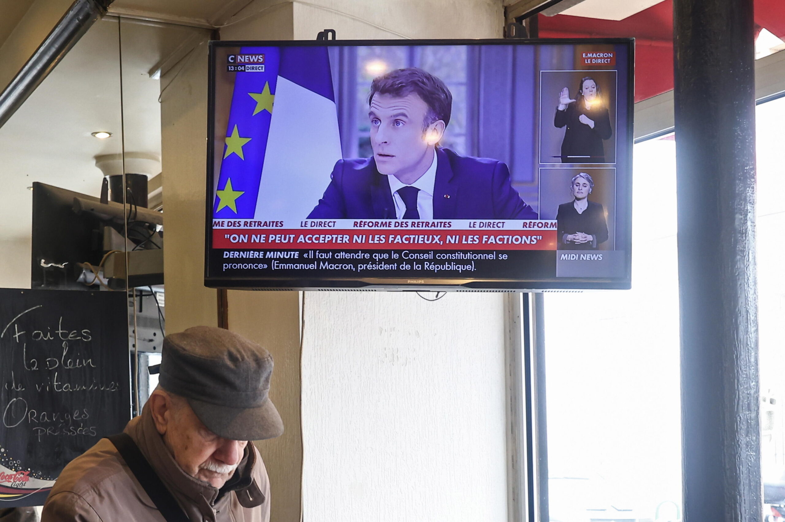 epa10536776 A television in a bar shows the French President Emmanuel Macron's televised interview, in Paris, France, 22 March 2023. Macron used the interview to defend his decision to raise the pension age from 62 to 64.  EPA/Mohammed Badra