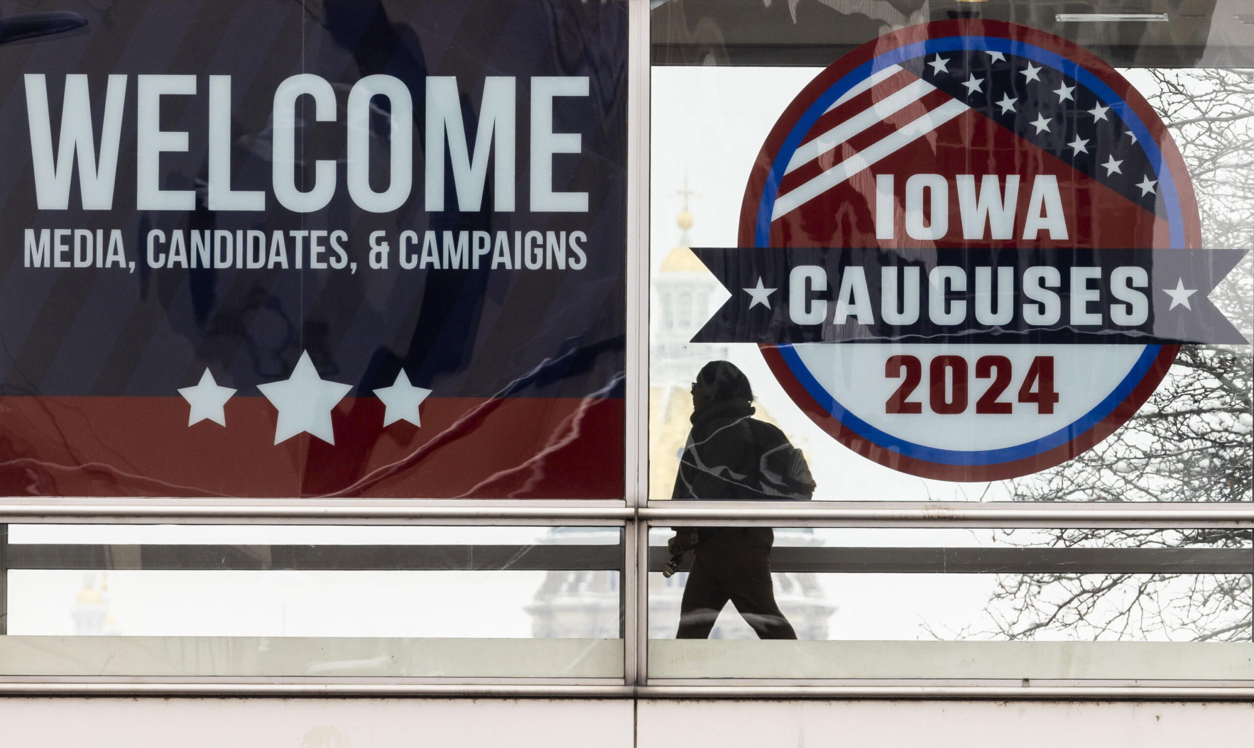epa11070019 A person walks past an Iowa caucus sign in Des Moines, Iowa, USA, 11 January 2024. Florida Governor Ron DeSantis, former South Carolina Governor Nikki Haley, and former President Donald Trump are campaigning across Iowa in the final days before the state holds its first-in-the-nation caucus on 15 January 2024.  EPA/JUSTIN LANE