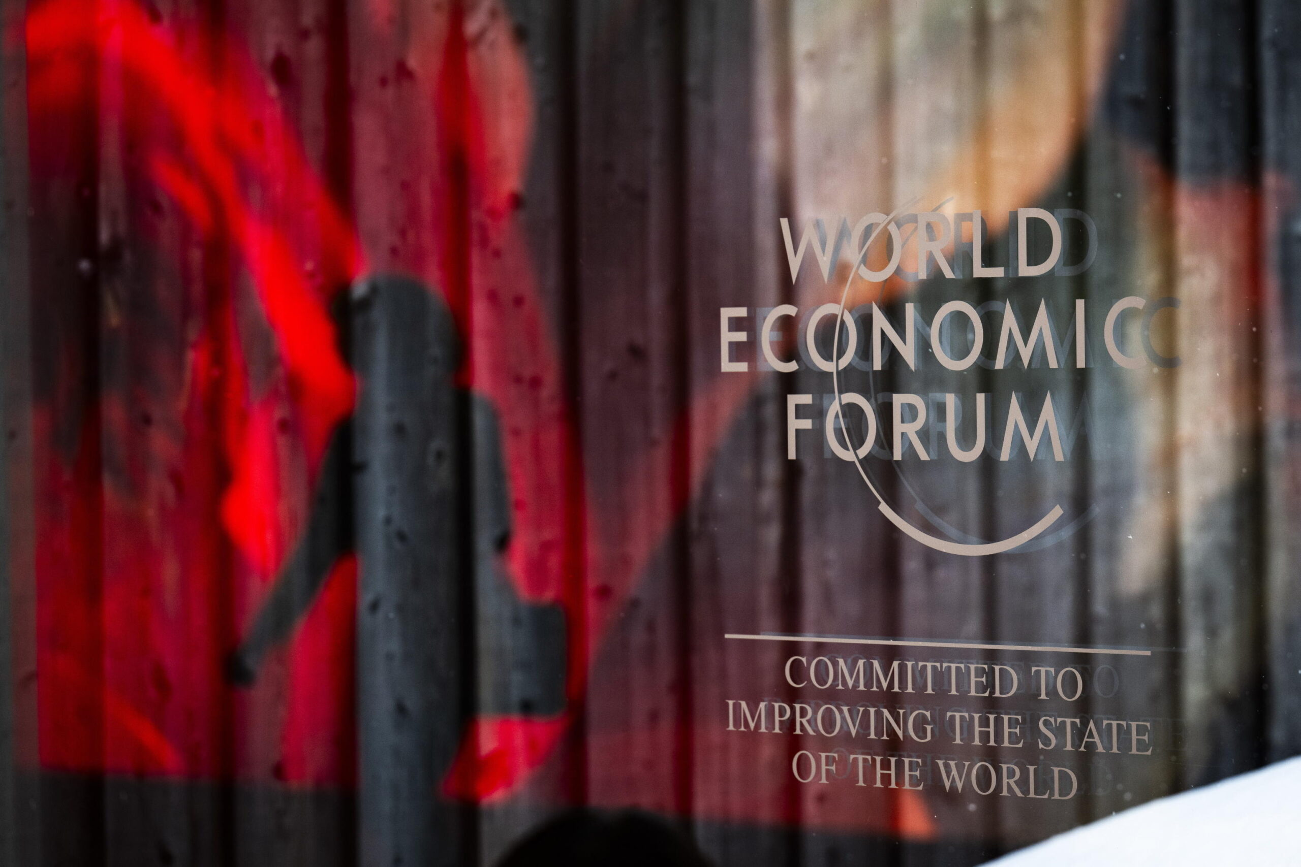 epa11089084 The logo of the WEF and a reflection of an AI generated projection are pictured as a woman passes by on the closing day of the 54th annual meeting of the World Economic Forum (WEF) in Davos, Switzerland, 19 January 2024. The meeting brings together entrepreneurs, scientists, corporate and political leaders in Davos under the topic 'Rebuilding Trust' from 15 to 19 January.  EPA/GIAN EHRENZELLER